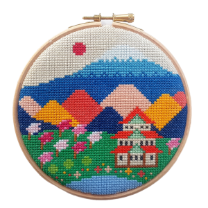 A cross stitch kit in a wooden hoop with a colourful image of Mount Fuji